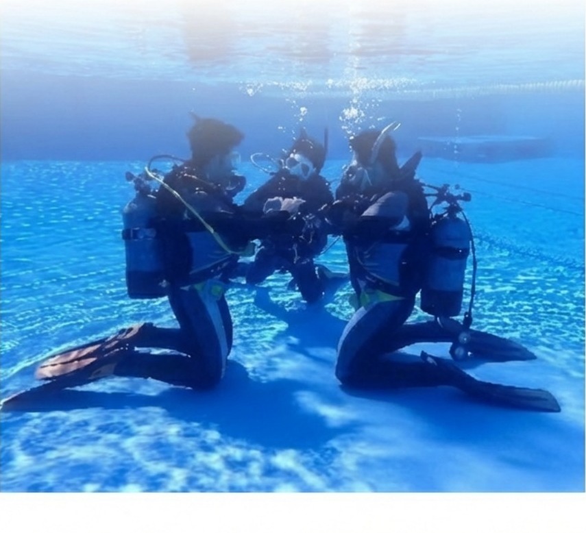 海中で向かい合って実習する2人のダイバー